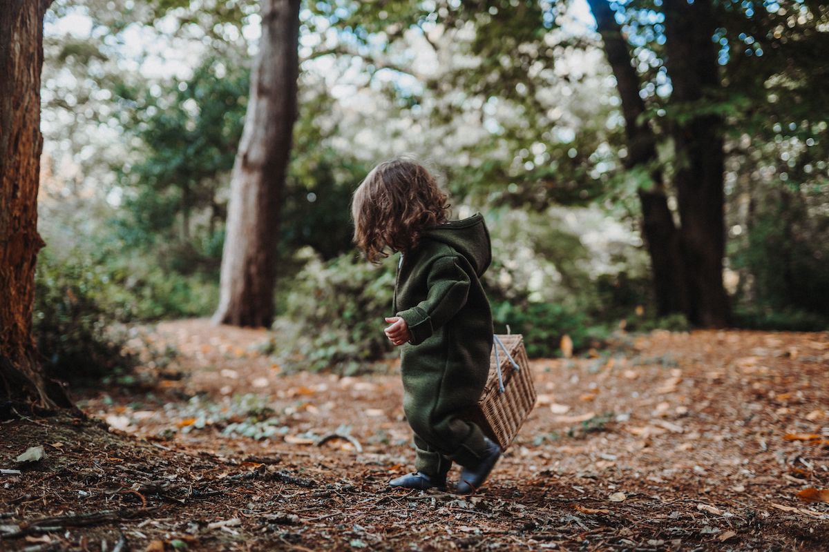 toddler in the woods in an olive disana boiled wool overall