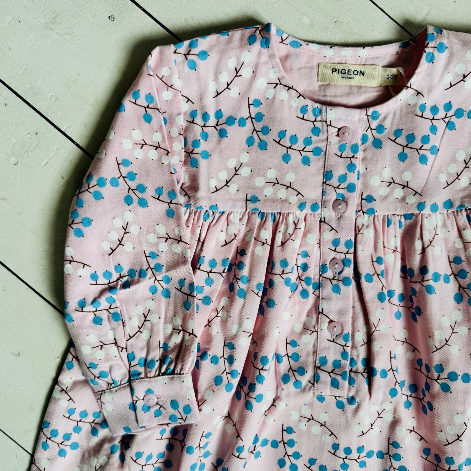 pigeon organics winter berry pink dress with blue and white berry motif close up