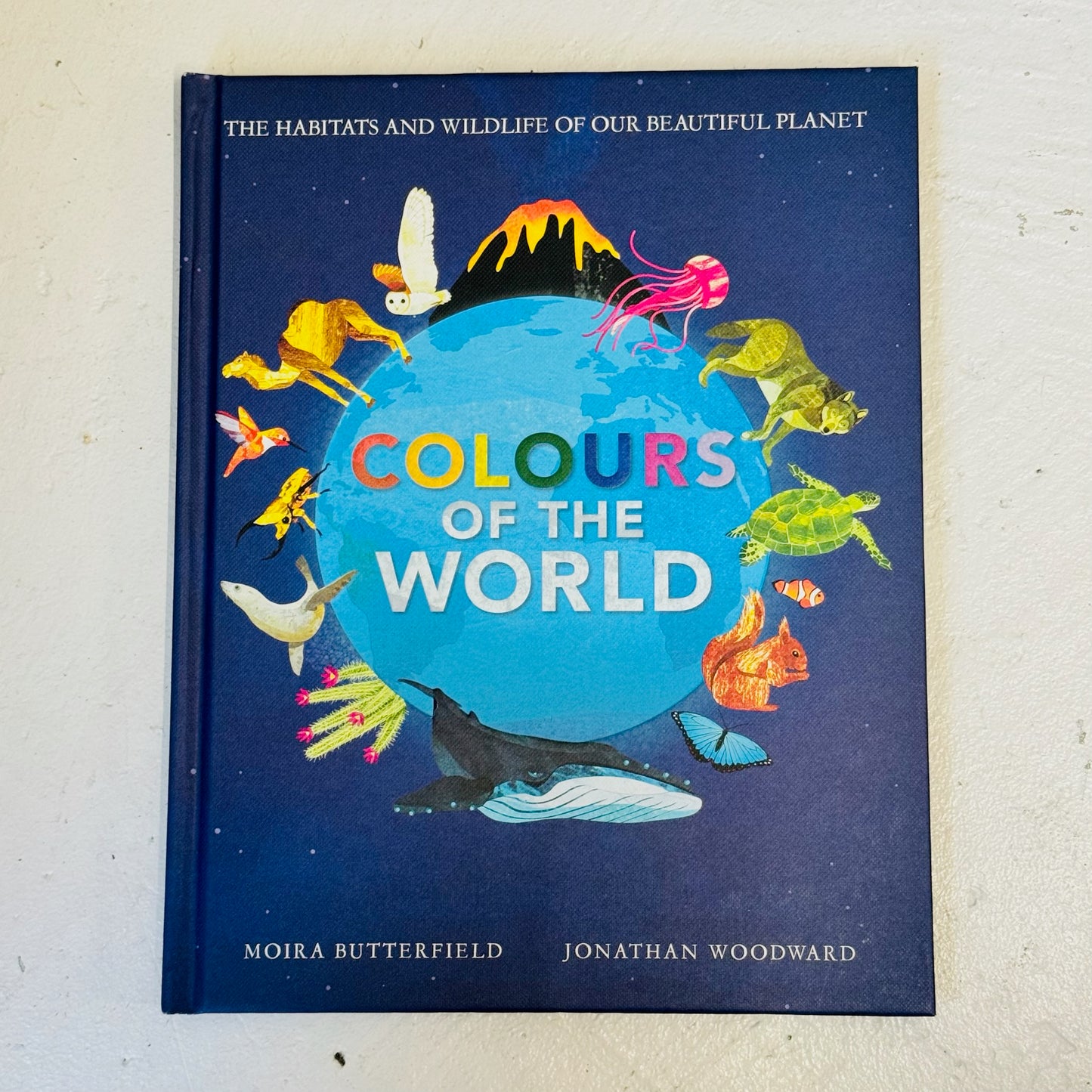 Book titled 'Colours of the World' with illustrations of animals around a globe on a blue background.