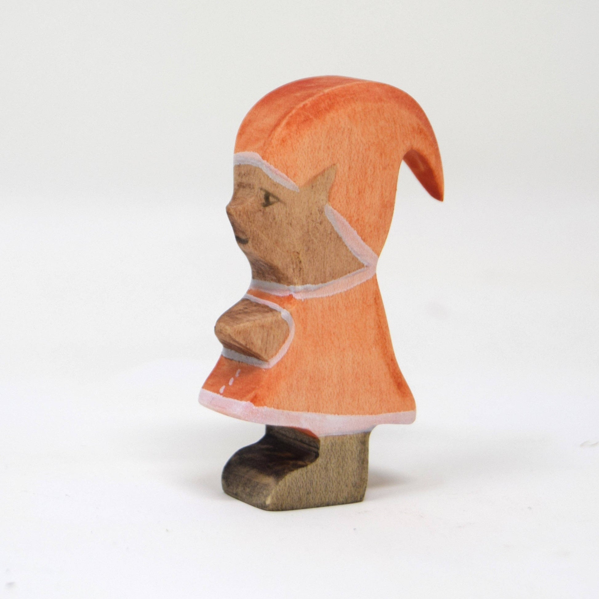 Wooden figurine of an elf wearing an orange hooded cloak on a white background