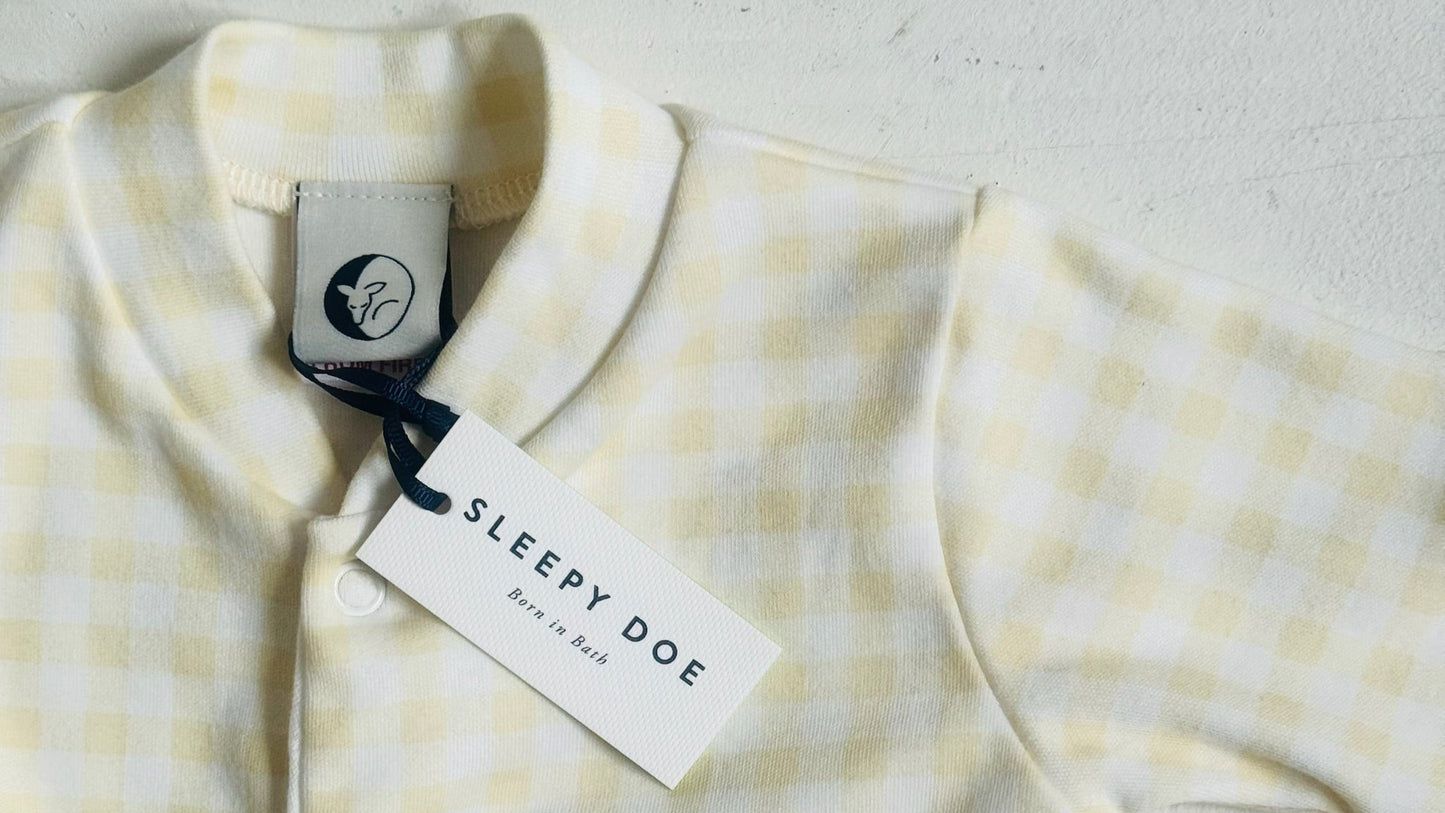 Yellow and white checkered baby outfit with 'Sleepy Doe' tag on a light background